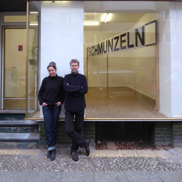 Simone Zaugg & Pfelder stehen vor einem Schaufenster mit dem Schriftzug Schmunzeln.