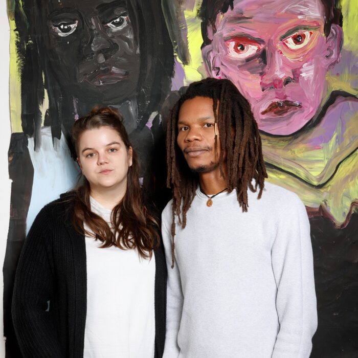 Lydia Schellhammer und Christ Mukenge stehen vor einem Werk, das sie beide zeigt