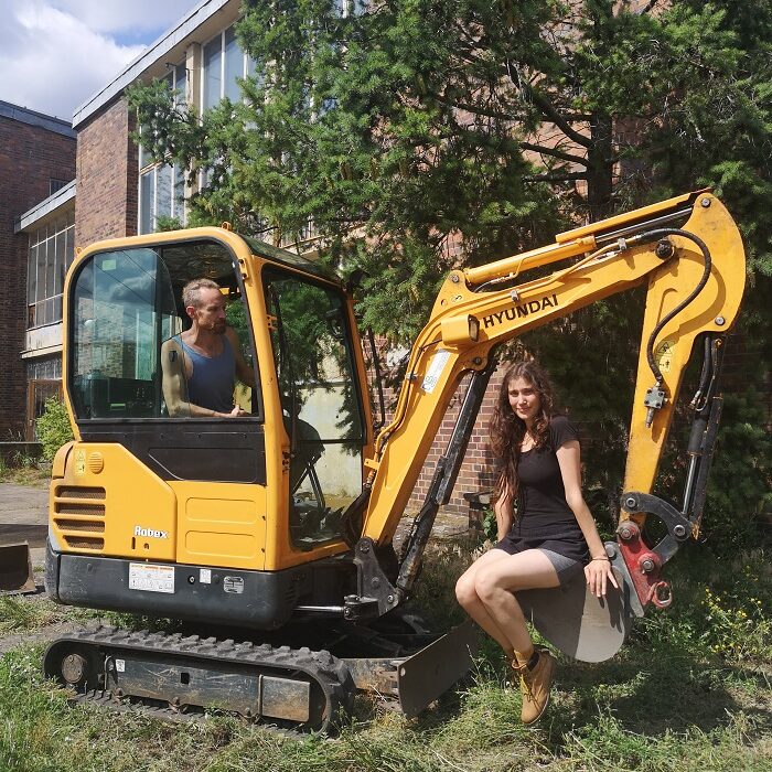 Ria Wank und Wolfgang Ganter sitzen auf einem Bagger.