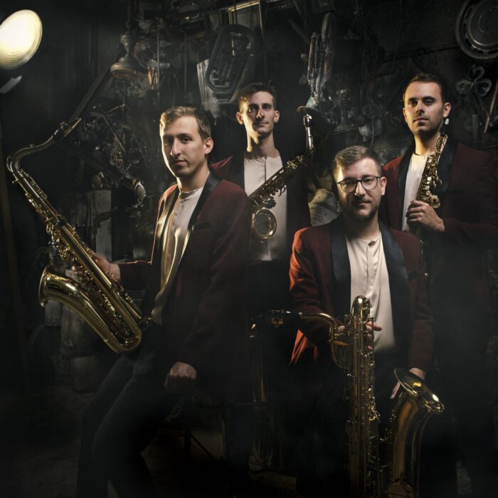 Das Saxophon-Quartett Kebyart trägt rote Jackets und hält ihre Instrumente in den Händen.
