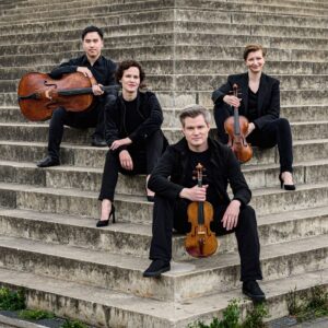 Das Notos Quartett sitzt auf einer Treppe und hält ihre Streichinstrumente in den Händen.